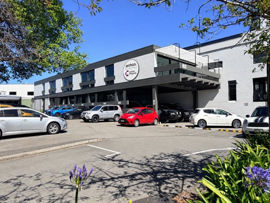 The Archco studio at 82 Oxford Terrace: a two-storey grey concrete-block building with a covered entry, the Archco sign on the upper wall and parking out the front.